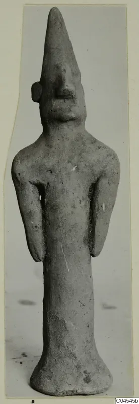 Standing terracotta figurine with a tall pointed head, narrow body and flared base, from Ayia Irini