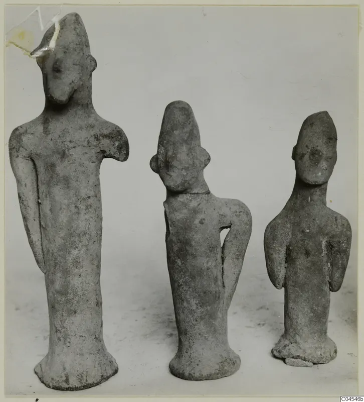 Three terracotta figurines of standing human figures shown side by side against a plain grey backdrop.