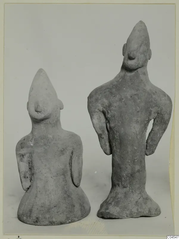 Two small terracotta human figurines with pointed heads and flared bases, standing side by side.