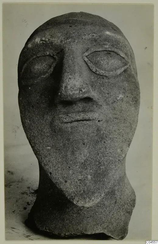 Front view of a grey stone head with almond-shaped eyes, a long nose and a thin mouth
