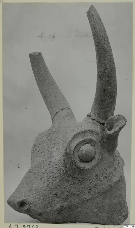 Terracotta animal head with two long curved horns, a round eye boss and rows of small impressed dots on the face