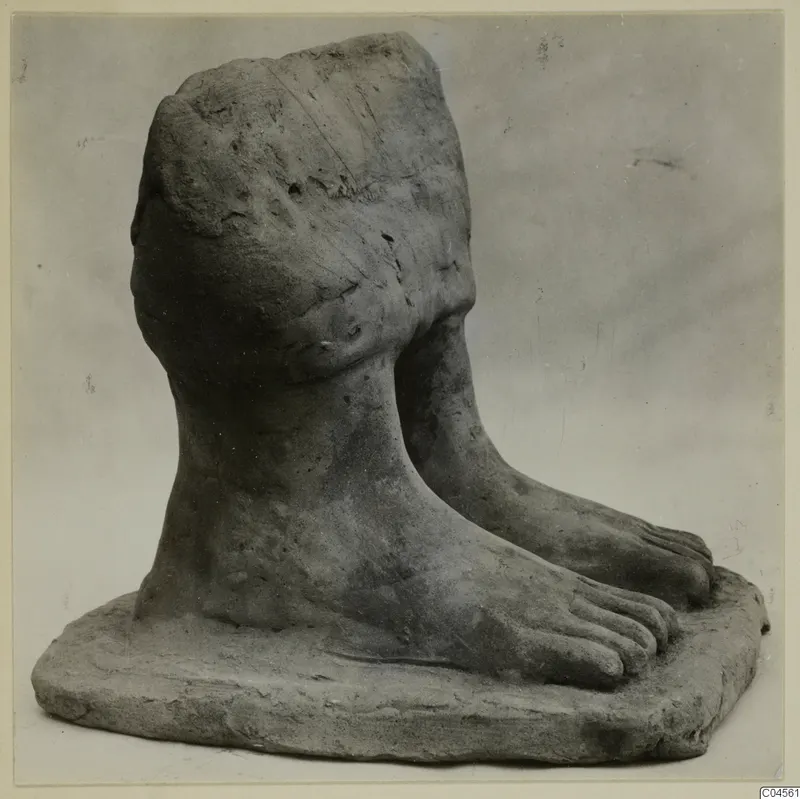 Terracotta fragment showing two bare feet with toes on a thick flat base, with a rounded modelled upper part