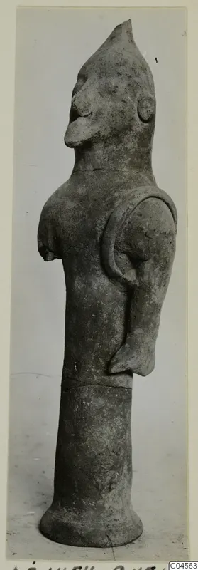 Terracotta figurine with a pointed head, large nose and a tall cylindrical lower part