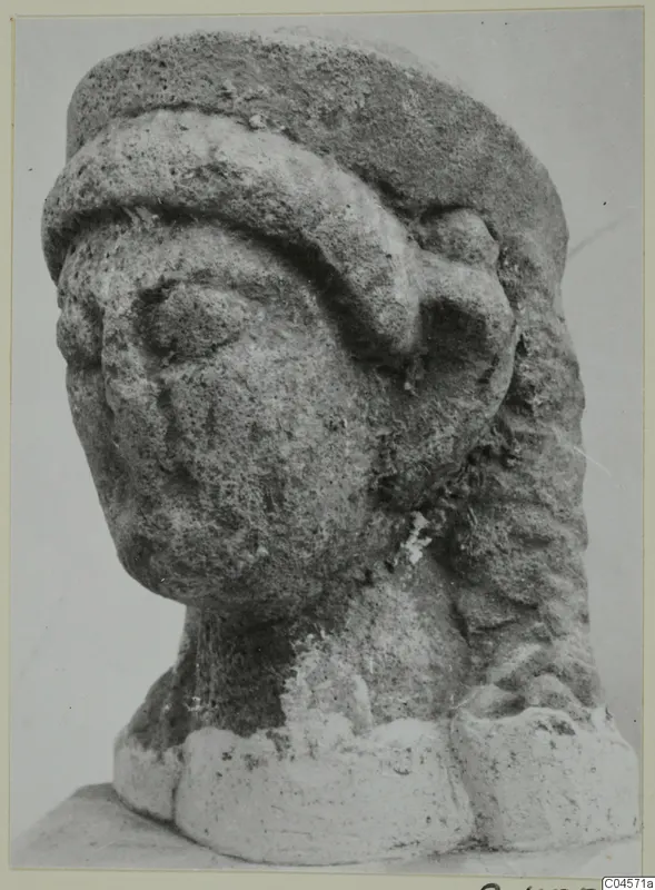 Limestone head from a statue from Arsos, with a worn face and a thick band across the brow.