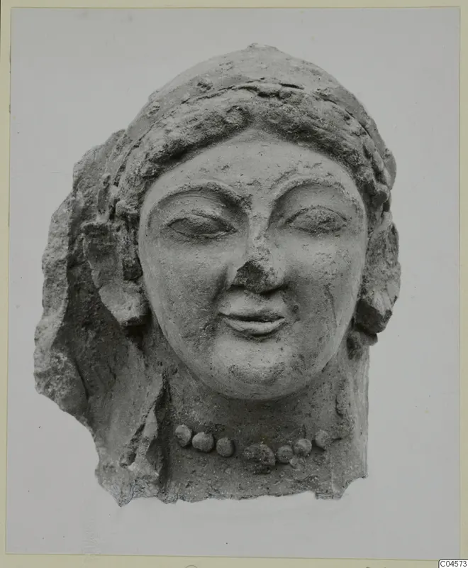 Terracotta head of a woman with a bead necklace, eyes half-closed and a slight smile, broken at the sides and back.