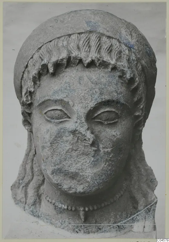 Limestone head of a figure from Arsos, with a hair band, a plain face and a beaded necklace.