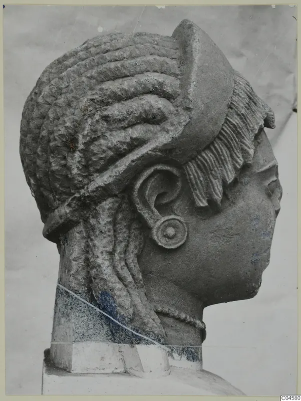 Limestone sculpture of a female head in profile, with elaborate curled hair and a large ear spiral, from Arsos.