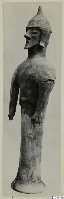 Terracotta figure of a helmeted standing figure on a tall cylindrical base, shown in profile against a grey backdrop.