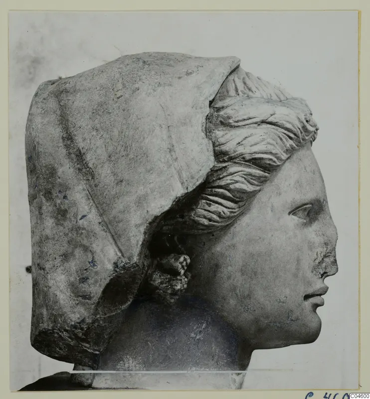 Carved stone head in right profile, with a veil over the head and a chipped nose.