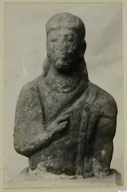 Limestone Proto-Cypriote bust with one arm bent across the chest and a worn, pitted face