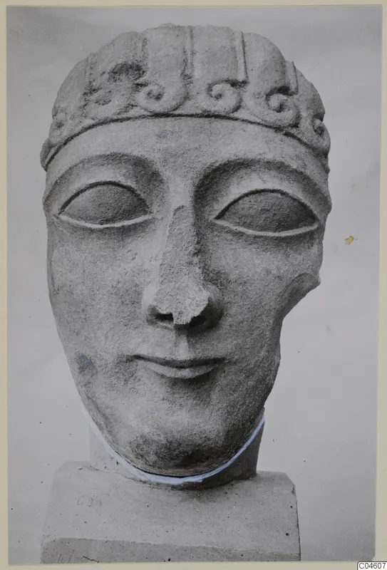 Limestone head sculpture with a band of spiral scrolls across the forehead, on a square block base.