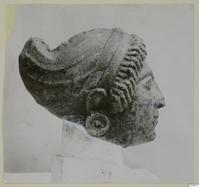 Limestone head from Arsos in profile, facing right, with a layered hair roll and a disc earring.