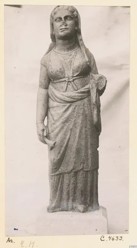 Standing stone statue of a draped female figure from Arsos, photographed against a plain backdrop.