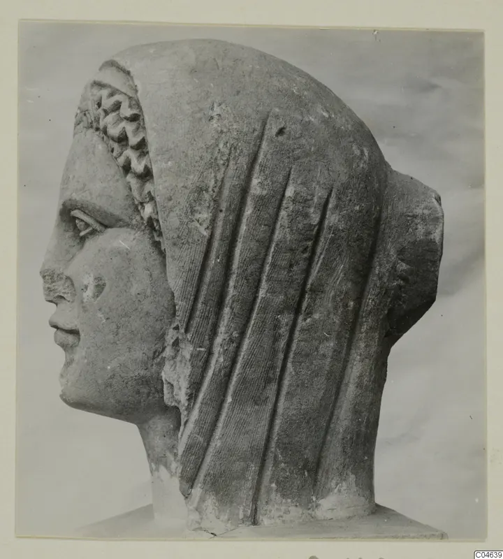 Stone sculpture of a head in profile facing left, with a veil falling in vertical folds and a wavy fringe at the forehead, from Arsos.