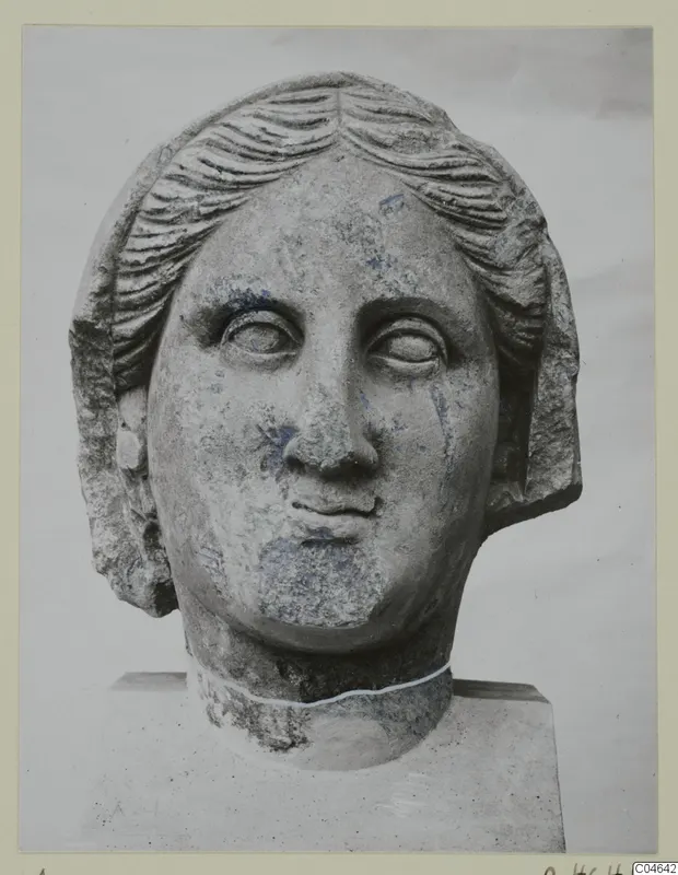Stone statue head from Arsos, front view, with wavy hair parted at the centre and drawn back over the ears.