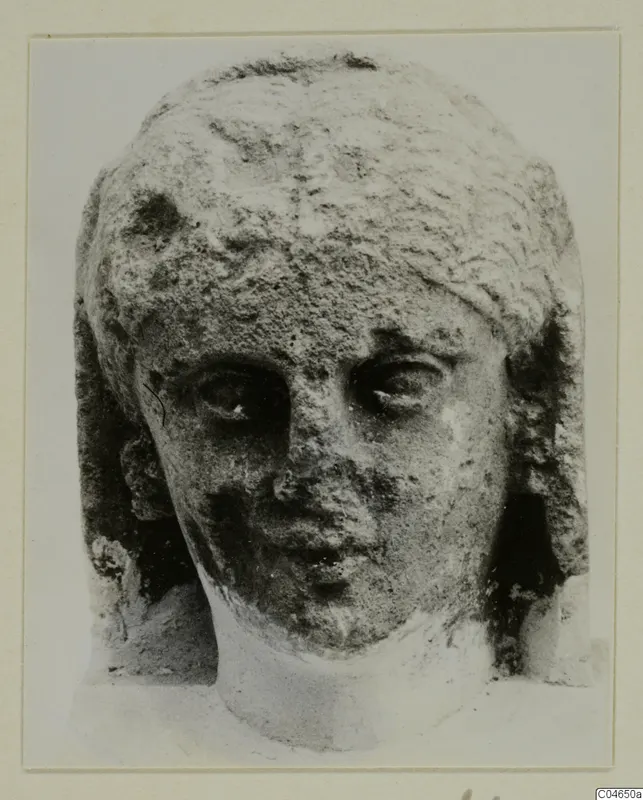 Stone head of a statue from Arsos, shown face on with worn features.