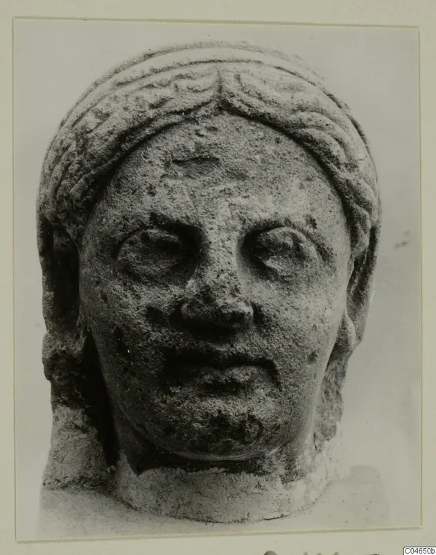 Stone head from Arsos, face and headdress carved in limestone, viewed from the front.