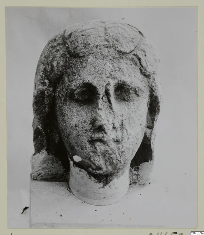 Stone head of a female figure from Arsos, with wavy hair and a broken neck, photographed against a plain background.