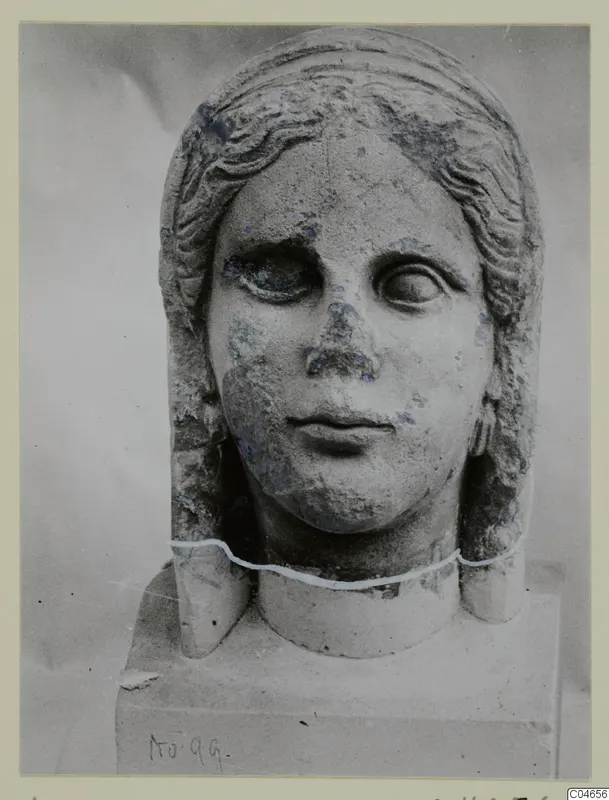 Stone statue head and neck from Arsos, with wavy hair framing the face and a block base