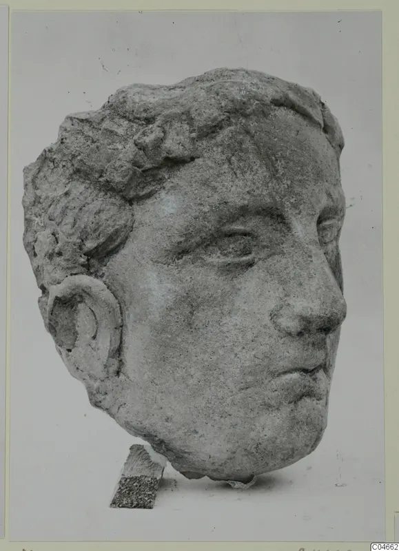 Carved stone head from Mersinaki with short curled hair and a rounded ear, shown against a plain backdrop