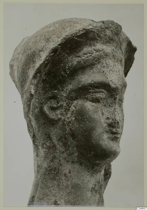 Head of a terracotta figure from Mersinaki, with a close-fitting cap and a worn, pitted surface