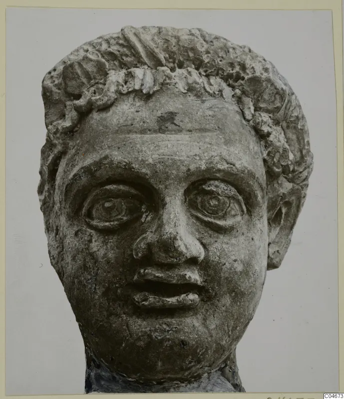 Carved stone head from Mersinaki with curled hair and large, wide-open eyes, seen from the front