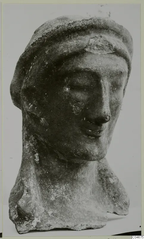 Carved head and upper body of a figure from Mersinaki, shown against a plain grey backdrop