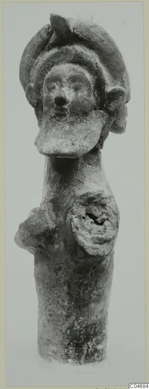 Terracotta figurine of an upright figure with a tall headdress, a broad face and a disc-shaped element on the chest