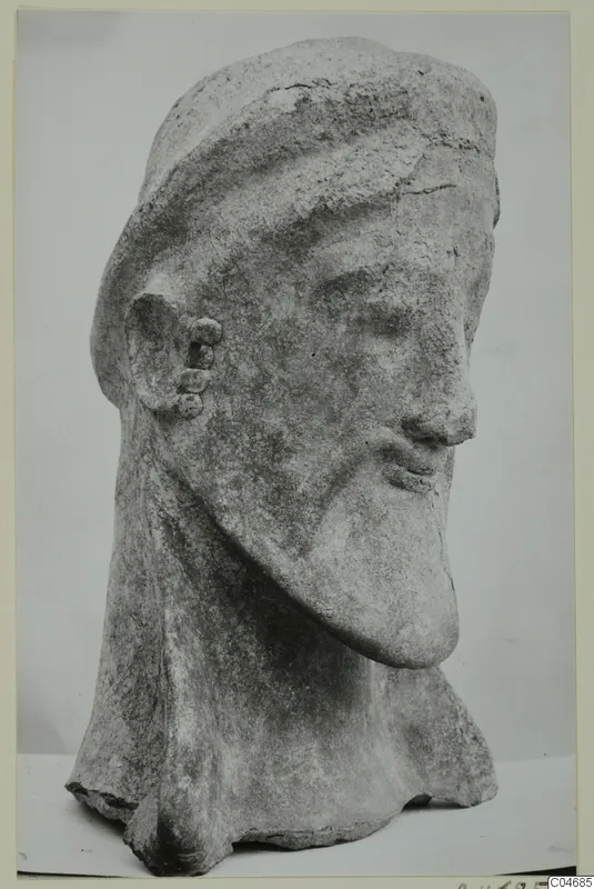 Terracotta head from Mersinaki with a close-fitting cap, long pointed beard and three round ornaments on the ear