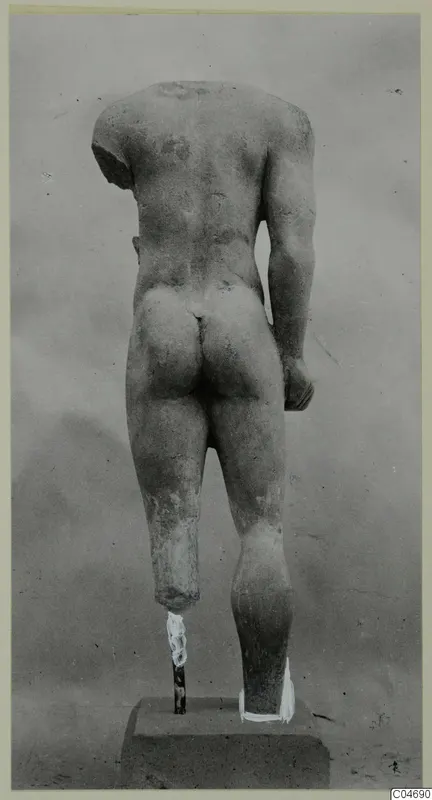 Back view of a headless limestone statue of a standing male figure, from Mersinaki