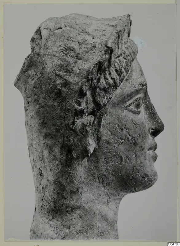 Profile view of a sculpted human head facing right, with wavy hair and a rough, weathered surface
