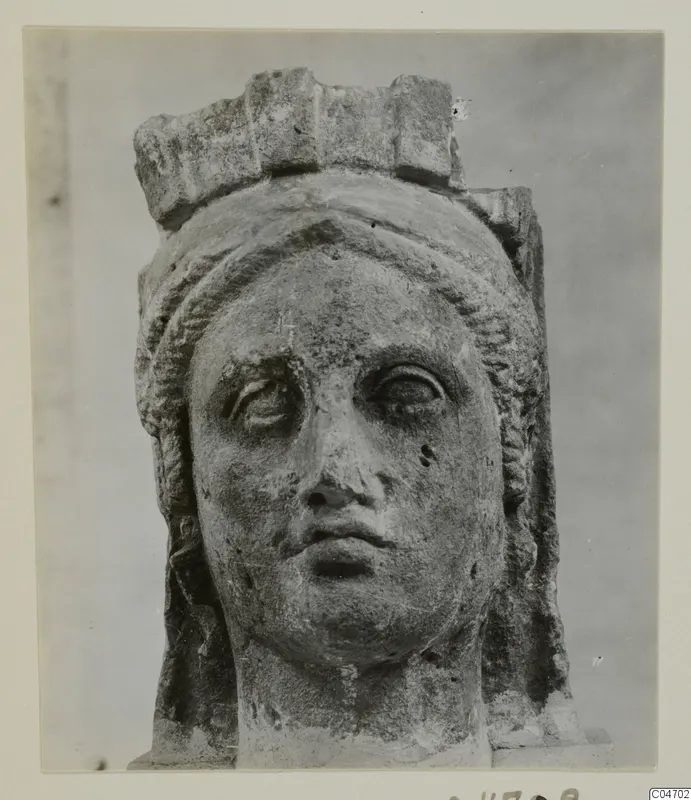 Stone head from Arsos with a flat crown-like top and wavy hair framing the face