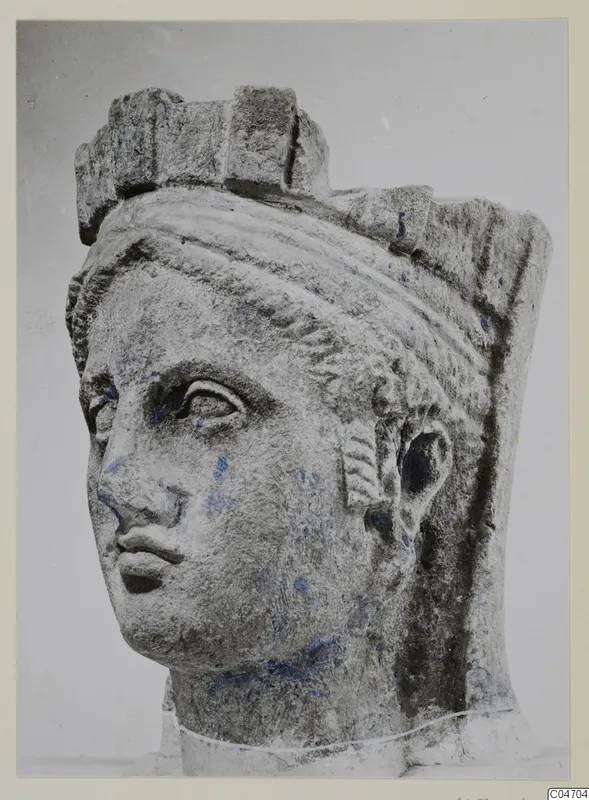 Stone head of a female statue from Arsos, showing a carved face with a polos-like headdress and blue paint traces.