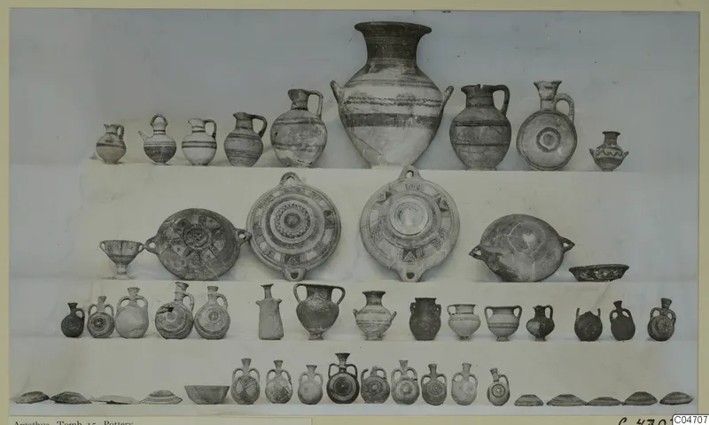 Pottery vessels from Amathus, Tomb 15, arranged in tiers on a light backdrop, with a large jar and many jugs and bowls