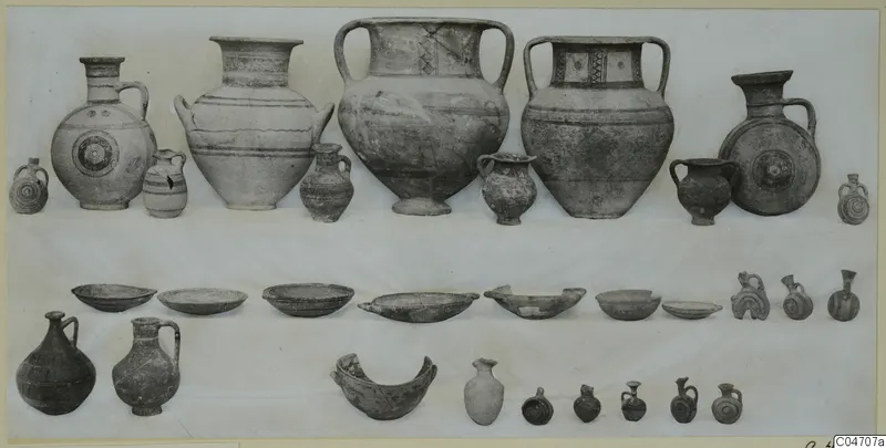 Group of pottery vessels from Amathus Tomb 18: jugs, jars, juglets and bowls arranged in rows on a light cloth.