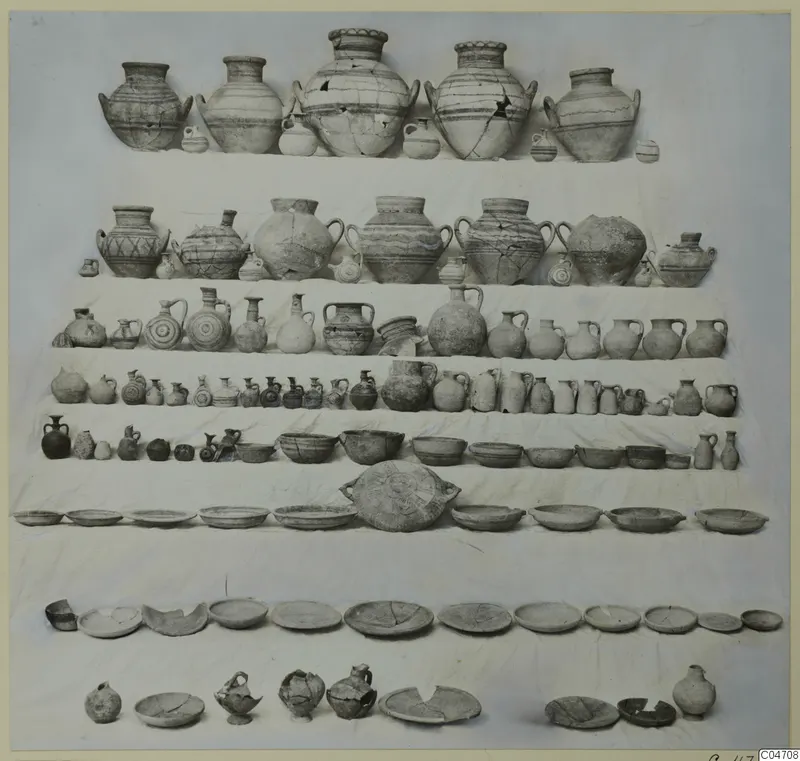 Pottery vessels from Tomb 8 at Amathus: jars, jugs, bowls and plates laid out in rows on a white cloth.