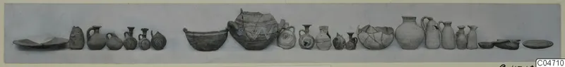 Row of pottery vessels from Amathus, Tomb 4, laid out in a line on a grey ground.