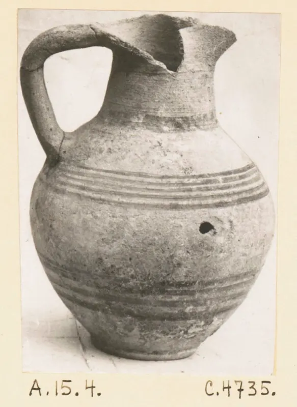 Pottery jug with a strap handle, a broken rim and dark horizontal bands on the body, catalogued as White Painted III-1