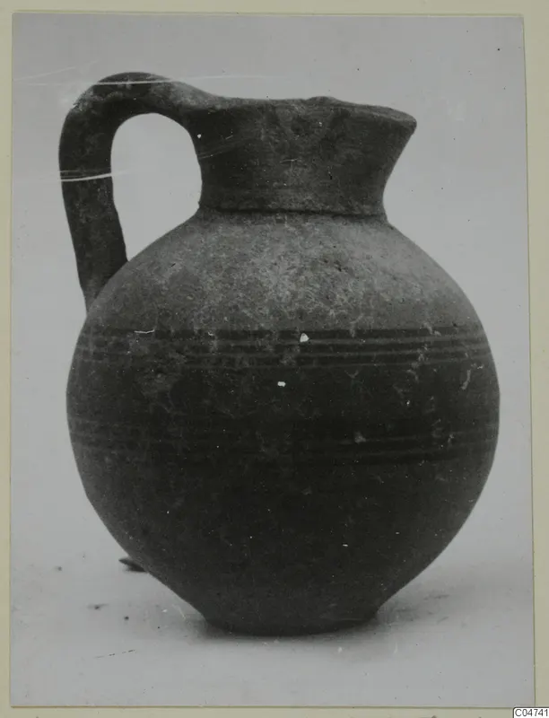 Pottery jug with a loop handle and dark banded decoration, from Amathus tombs, shown on a photo mount