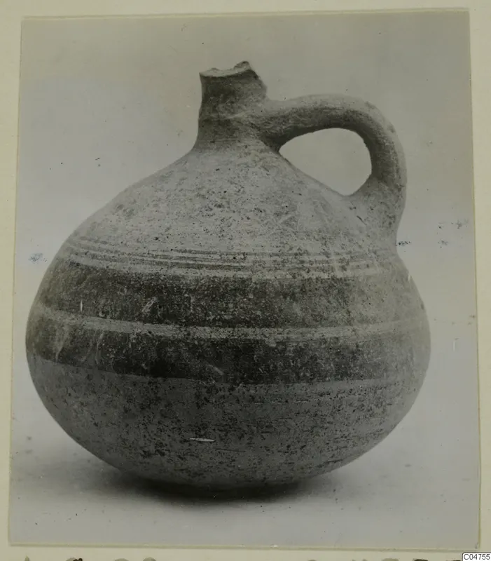 Pottery Bichrome IV jug with a broken neck, a strap handle and horizontal bands around the body, seen from the side