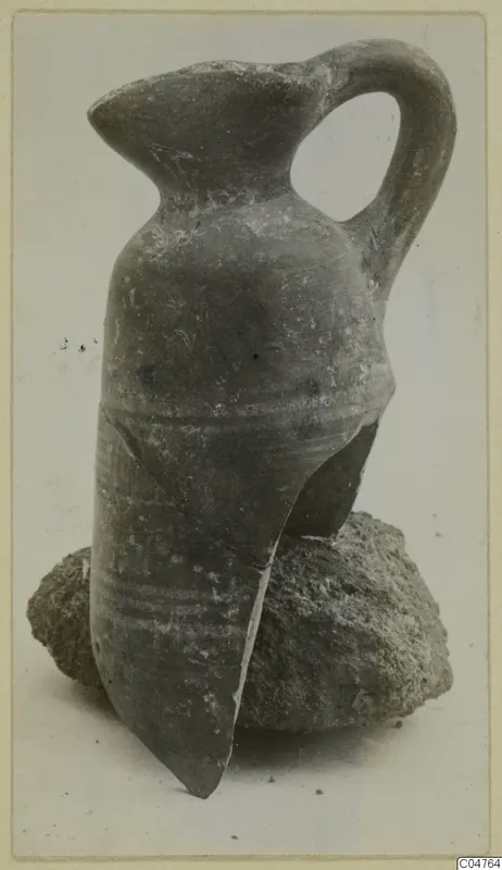 Pottery juglet with a strap handle, leaning on a lump of soil, from Amathus