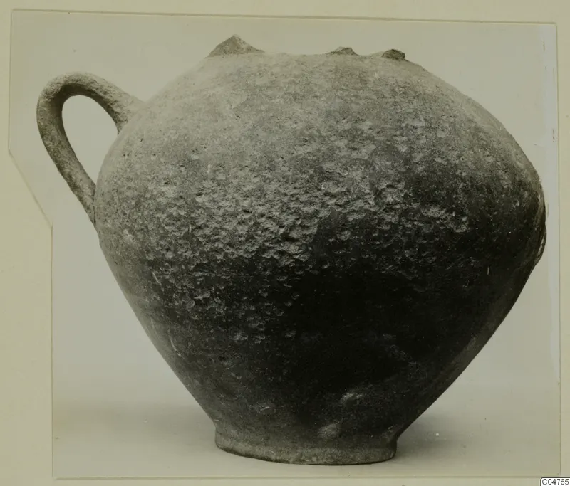 Round one-handled pottery vessel with a dark, pitted surface, from the Amathus tomb finds