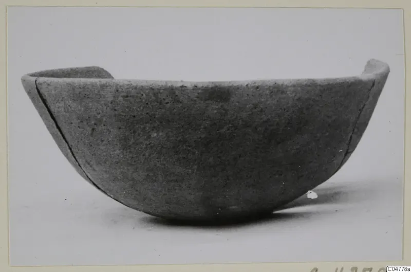 Plain pottery bowl with a rounded body and uneven rim, seen from the side.