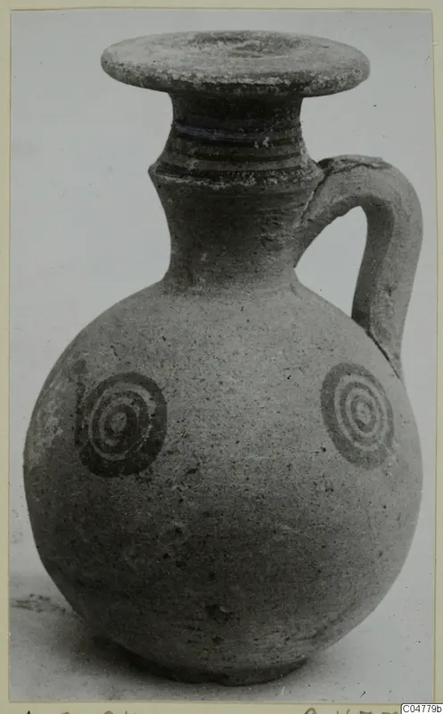 Pottery White Painted IV jug with a round body, strap handle and two concentric-circle motifs