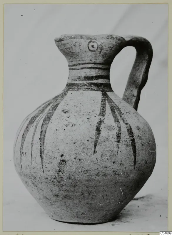 Pottery jug with a single handle, dark painted bands on the neck and shoulder, and long strokes down the body