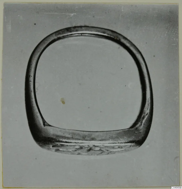 Finger ring from Enkomi with a wide flat bezel, photographed face-on against a plain grey background