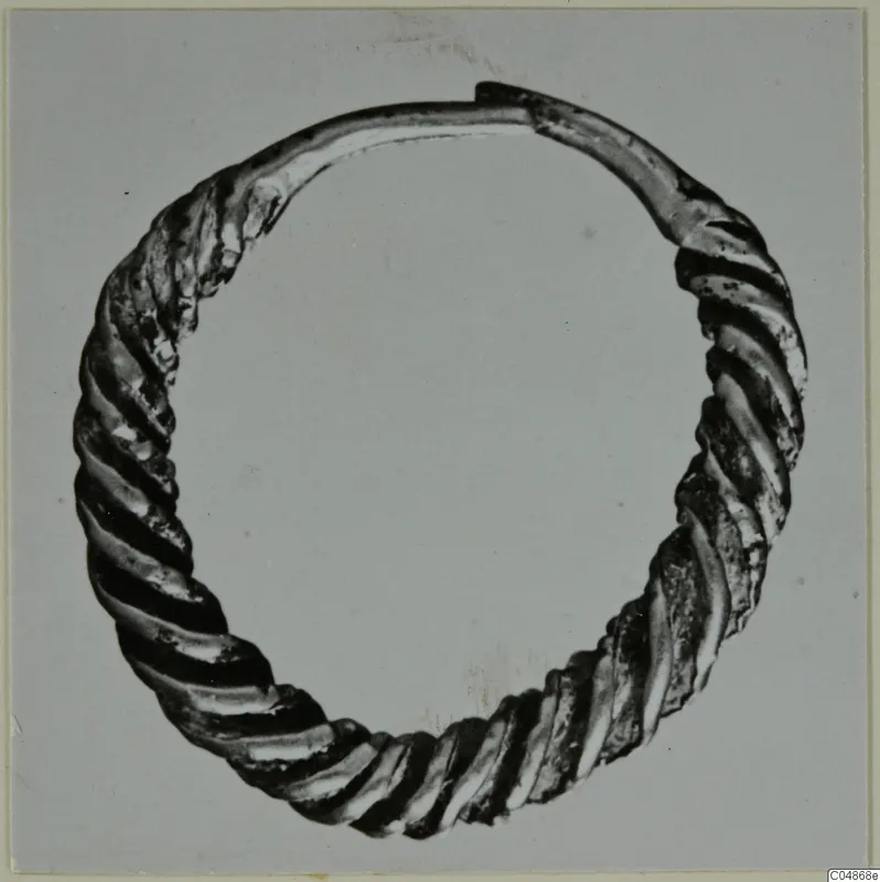 Twisted metal ring with a plain-ended gap, photographed against a grey background.