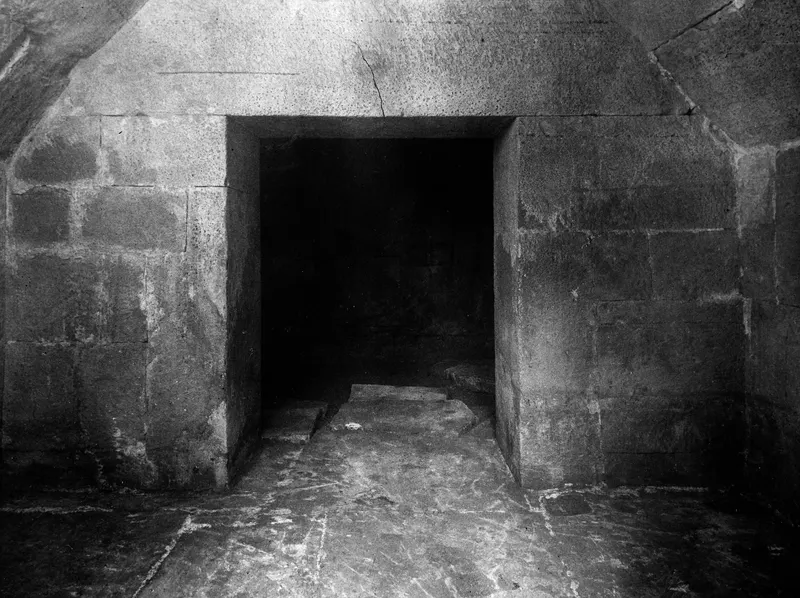 Interior of Tomb 2 at Amathus, looking through a doorway into the dark chamber beyond.