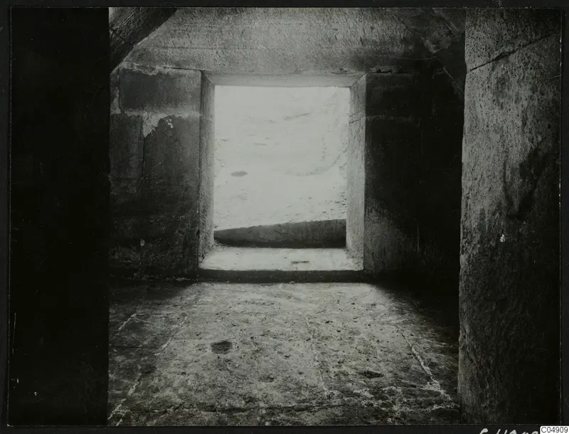 Interior of a stone chamber at Amathus, looking out through a square doorway to bright ground beyond.
