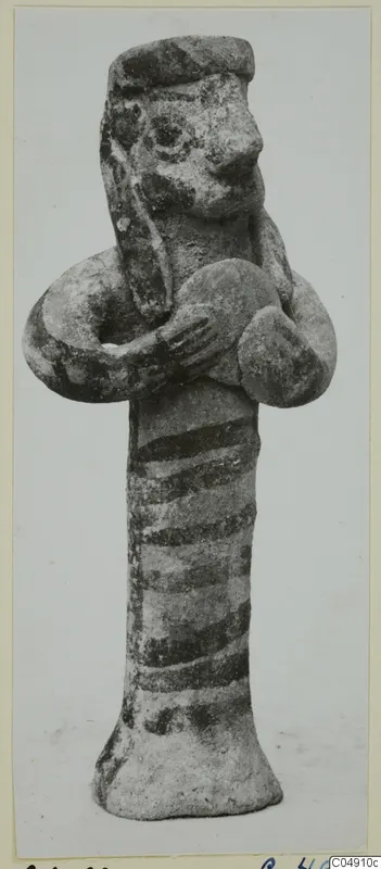 Terracotta figurine of a standing figure with a cap-like head, arms bent at the chest and dark painted bands on the body.